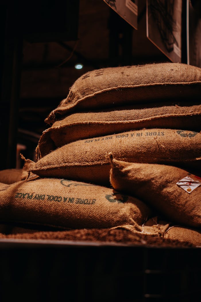 A close-up shot of stacked burlap sacks in an indoor warehouse setting.