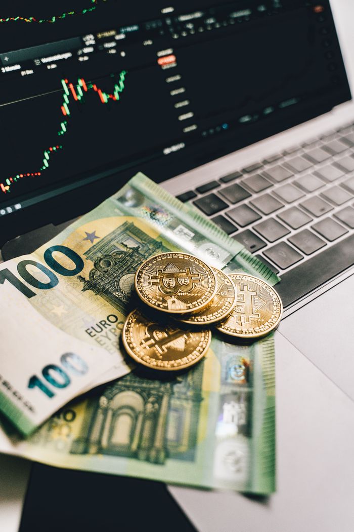 Services Euro banknotes and Bitcoin coins on a laptop, showcasing finance and cryptocurrency trends.